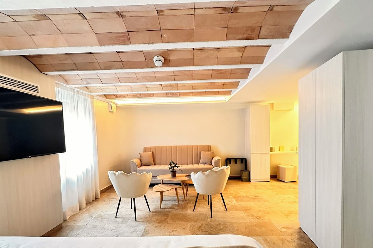 Una habitación moderna con techo inclinado, un conjunto de sofás, una mesa de comedor con sillas y una cama.
