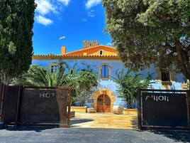 Un edificio tradicional con fachada azul, una chimenea de piedra y una puerta de madera.