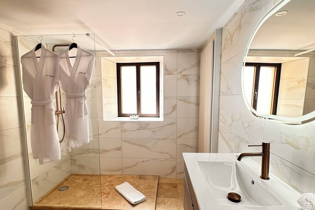 A modern bathroom with a walk-in shower, a large mirror, and a vanity with a sink.