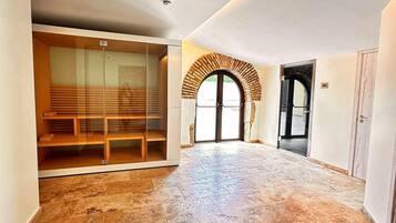 Una habitación amplia con piso de baldosas, un separador de vidrio y un banco de madera.