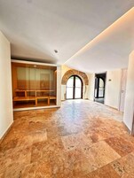 Una habitación amplia con piso de baldosas, un separador de vidrio y un banco de madera.