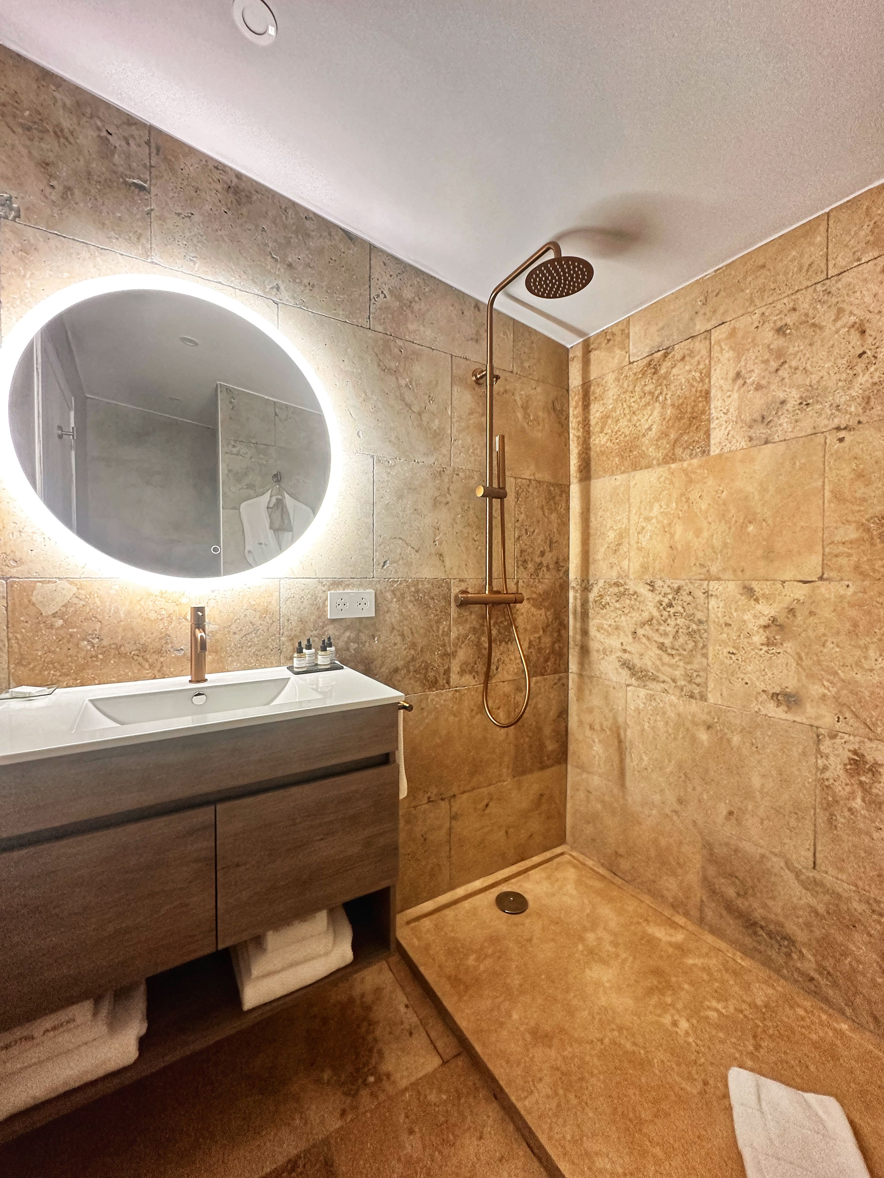 Une salle de bain moderne avec un grand miroir, un lavabo et un espace douche.