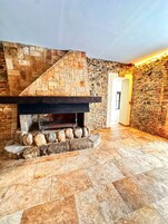 Una chimenea de piedra con diseño en espiga, rodeada por un borde de piedra y un suelo de baldosas.