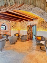 Un rincón de descanso acogedor con paredes de piedra, vigas de madera y asientos modernos.