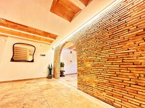 A hallway with a brick wall, a potted plant, and a tiled floor. - Boutique Hotel Comtal Empuries (Castello d'Empuries)