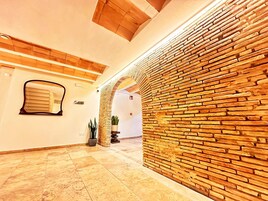 Un pasillo con pared de ladrillo, una planta en maceta y suelo de baldosas.