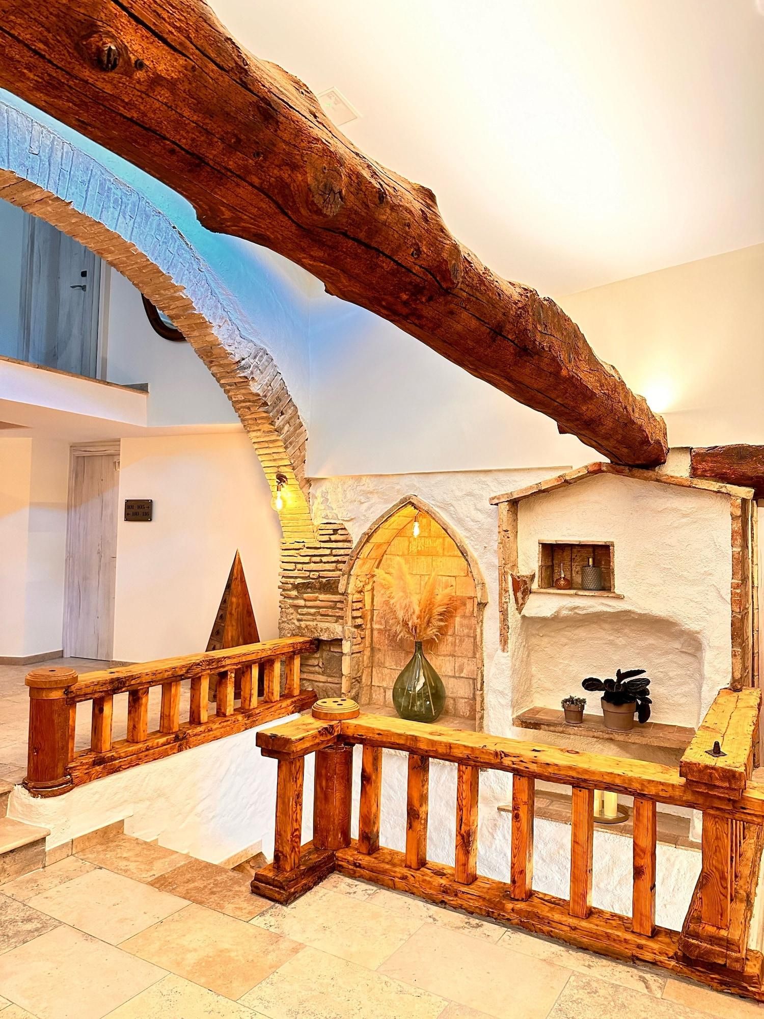 A rustic interior with exposed stone walls, wooden beams, and a stone staircase.