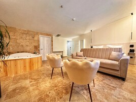 Una sala de estar moderna con un sofá color beige, dos sillones, un ventanal grande y un jacuzzi integrado.