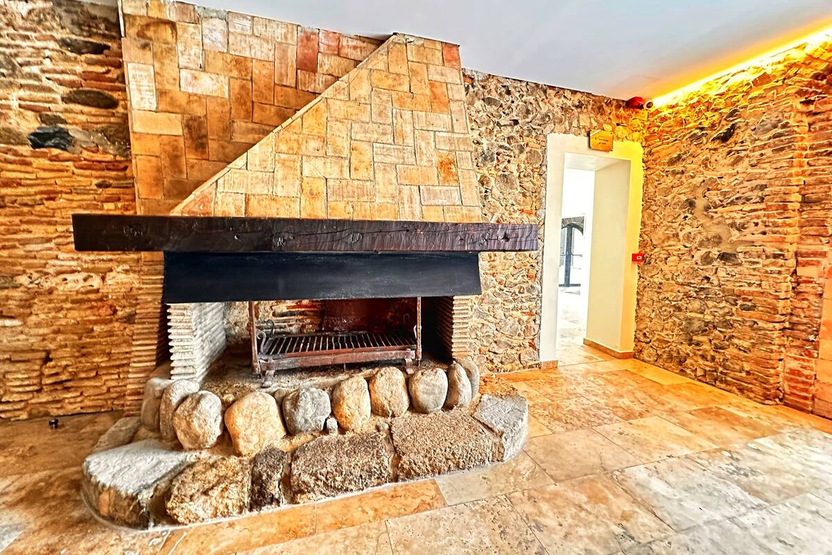 A stone fireplace with a wooden mantel and a stone surround.