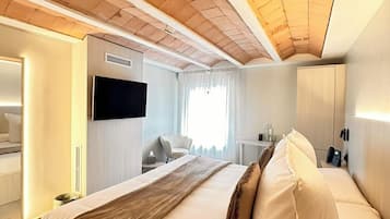 A hotel room with a large bed, a TV, a desk, and a wardrobe.
