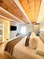 Una habitación de hotel con una cama grande, televisión, escritorio y armario.