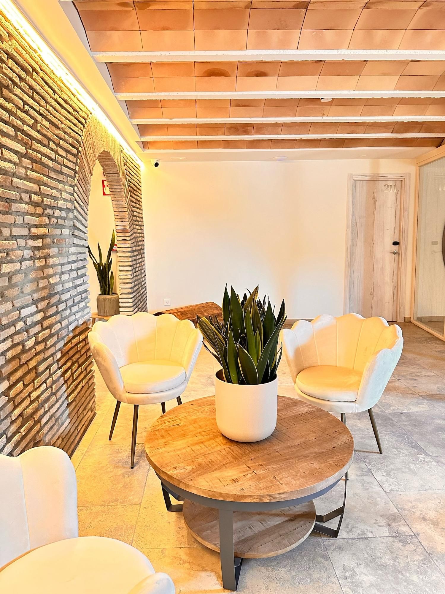 Un intérieur moderne avec un mur en briques, deux chaises blanches, une table ronde en bois et une plante en pot.