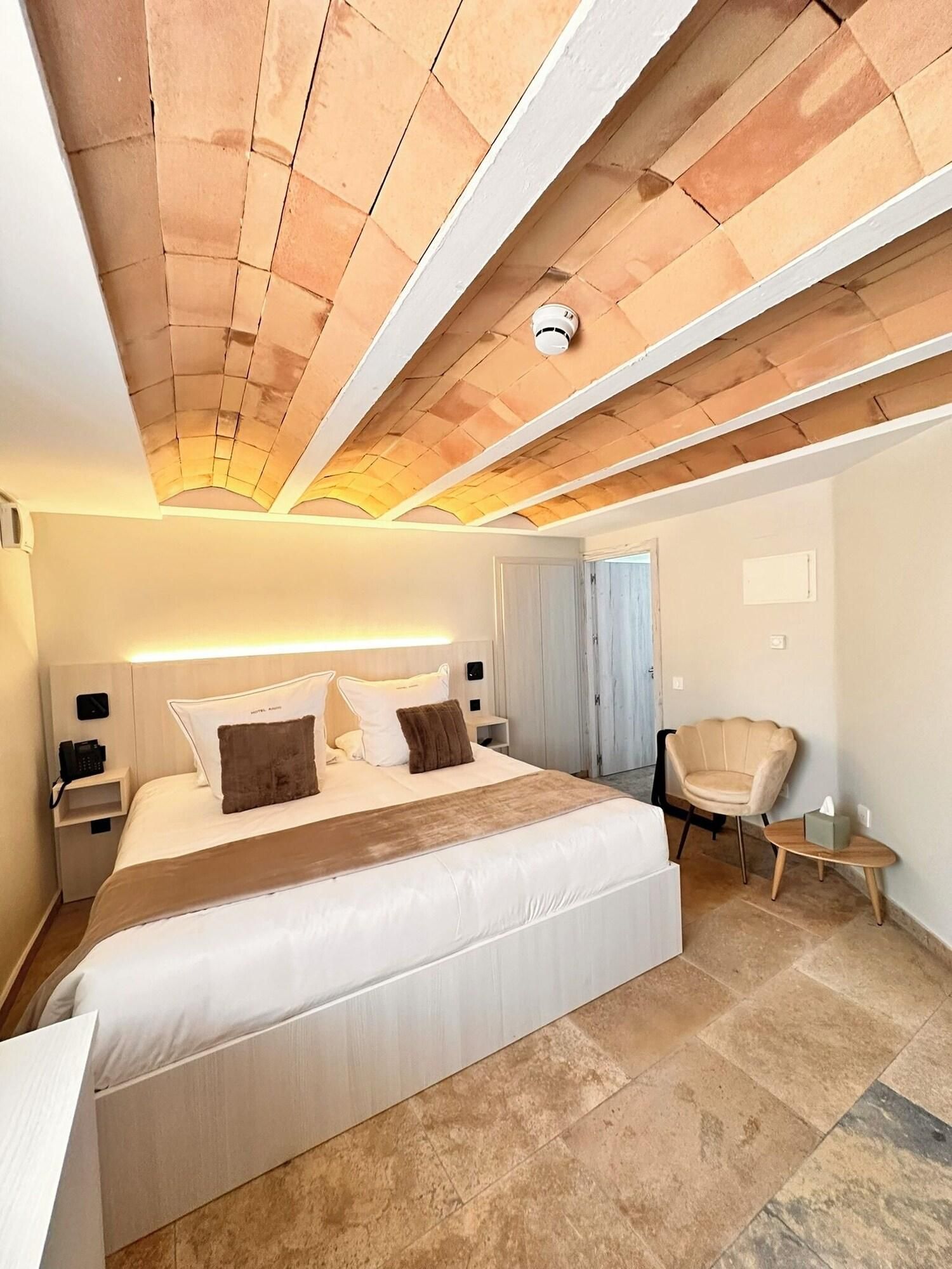 Une chambre d’hôtel avec un grand lit, une table de chevet avec un téléphone, une chaise et une petite table sur laquelle se trouve une boîte de mouchoirs.