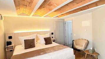 Une chambre d’hôtel avec un grand lit, une table de chevet avec un téléphone, une chaise et une petite table sur laquelle se trouve une boîte de mouchoirs.