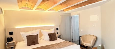 A hotel room with a large bed, a bedside table with a phone, a chair, and a small table with a tissue box.