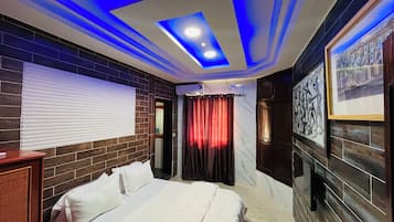 Habitación de hotel con cama, ventana con persianas, aire acondicionado de pared y techo con iluminación azul.