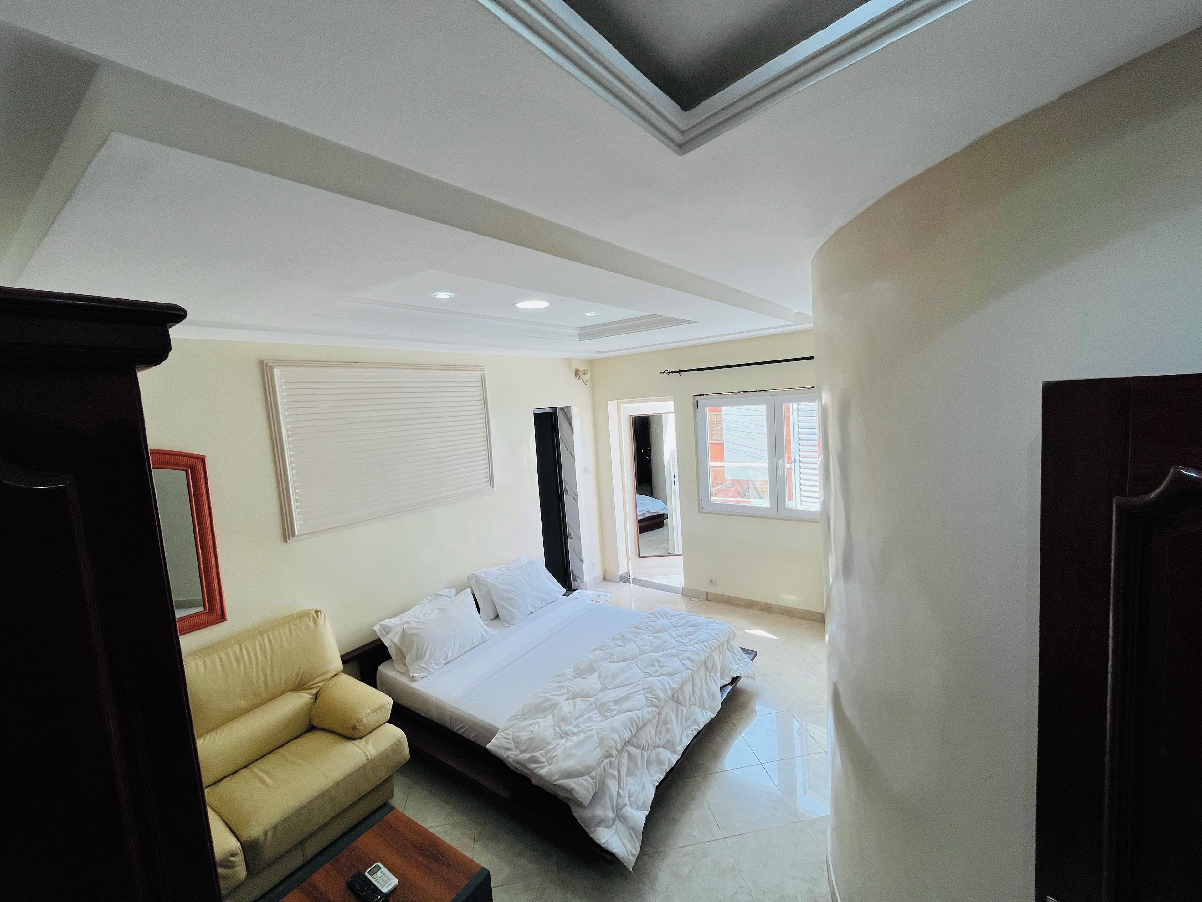 Un dormitorio con una cama, un sofá, una mesita de noche y una ventana.