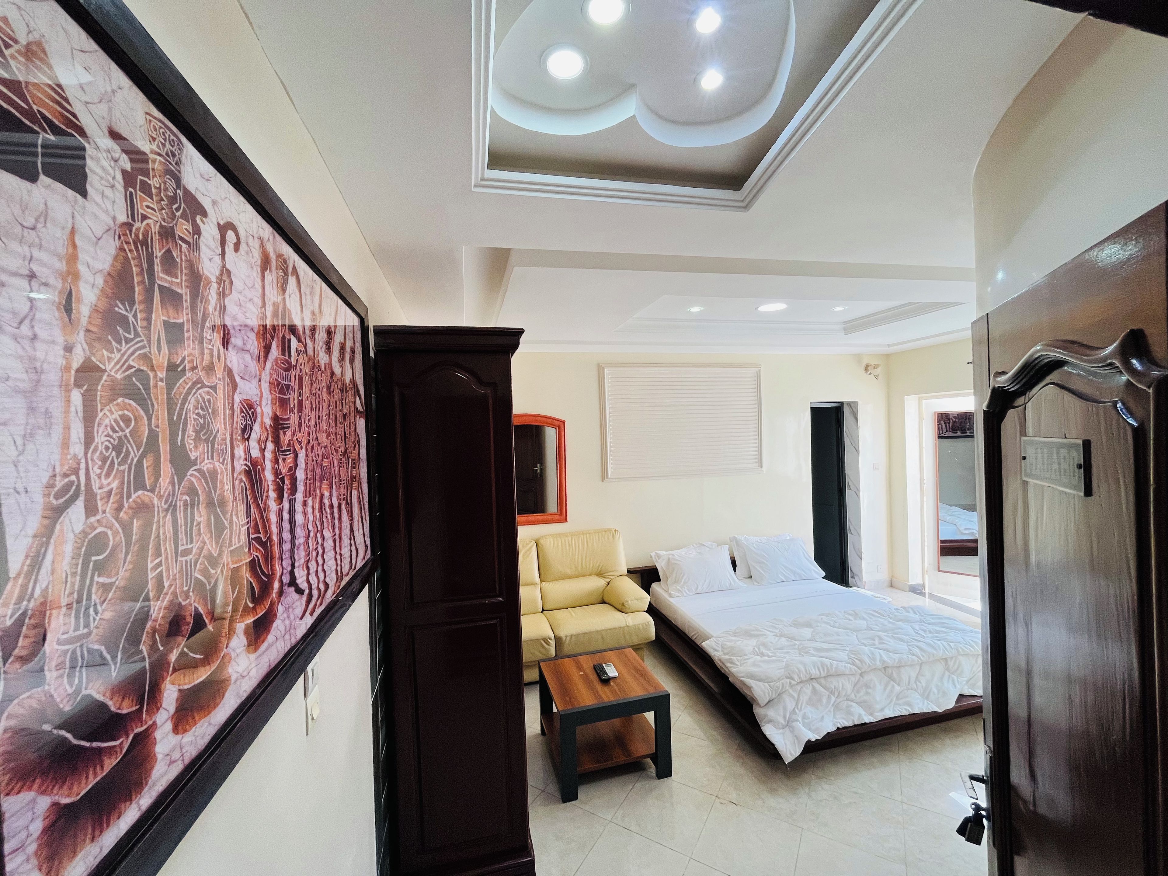 A hotel room with a bed, a sofa, a coffee table, and a large framed picture on the wall.