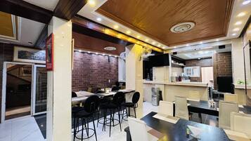 Um restaurante moderno com parede de tijolos, teto de madeira e várias mesas e cadeiras.