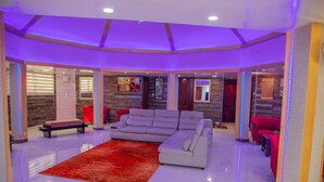 A spacious living area with a large grey sectional sofa, a red rug, and a red armchair. - Hotel Darou Khoudoss (Dakar)