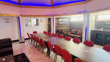 Un salón de conferencias con una mesa larga, sillas rojas y un diseño moderno en el techo.