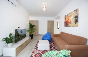 A modern living room with a flat-screen TV, a sofa, a bean bag, a coffee table, and a painting on the wall. - Vitan Central Oasis Bucharest (Bucharest)