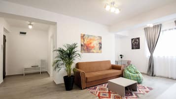 A modern living room with a brown sofa, a coffee table, a potted plant, and a colorful rug.