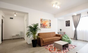 A modern living room with a brown sofa, a coffee table, a potted plant, and a colorful rug.