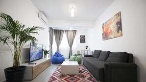 A modern living room with a sofa, a coffee table, a TV, and a potted plant. - Vitan Central Oasis Bucharest (Bucharest)