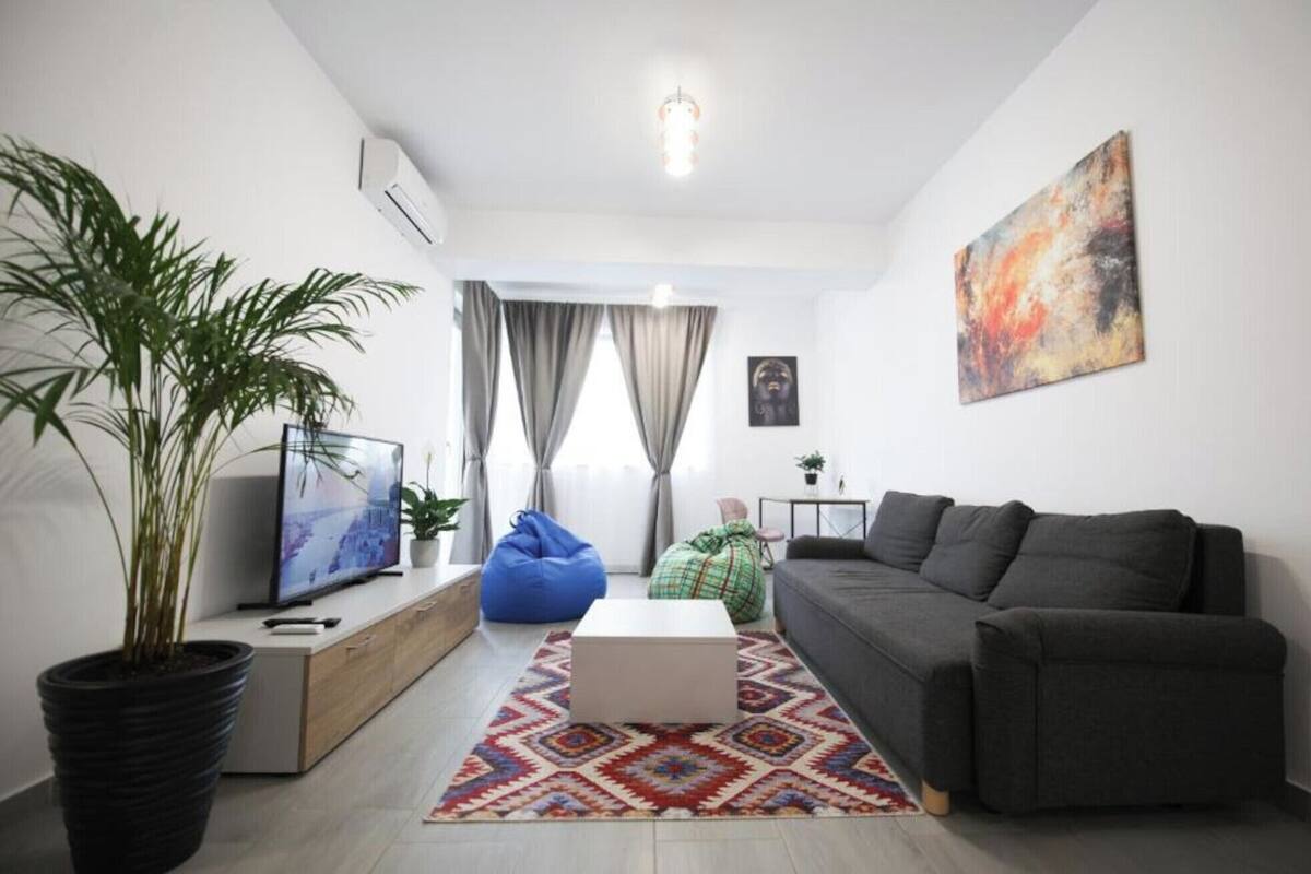 Una sala de estar moderna con un sofá, una mesa de centro, un televisor y una planta en maceta.