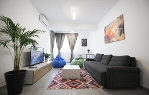 A modern living room with a sofa, a coffee table, a TV, and a potted plant. - Vitan Central Oasis Bucharest (Bucharest)