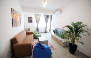 A modern living room with a sofa, a bean bag, a flat-screen TV, and a potted plant. - Vitan Central Oasis Bucharest (Bucharest)