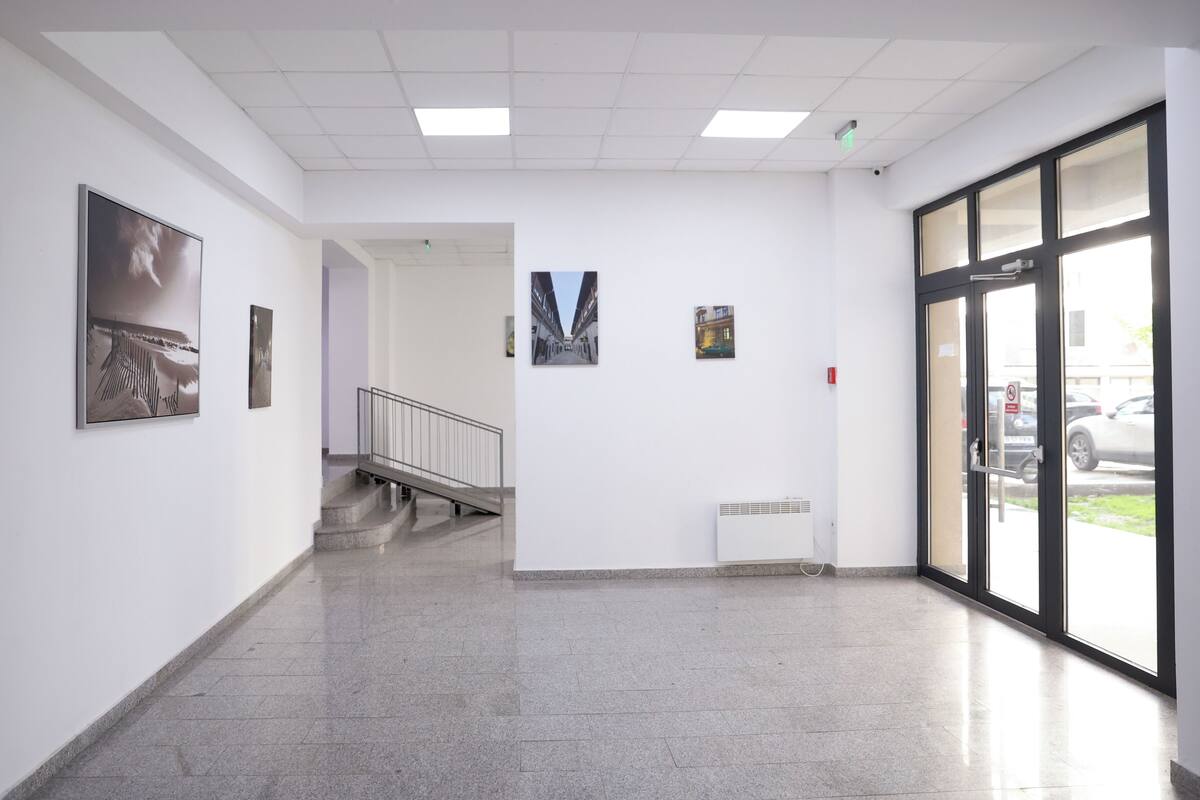 Un pasillo con una escalera, un radiador y cuadros en las paredes.