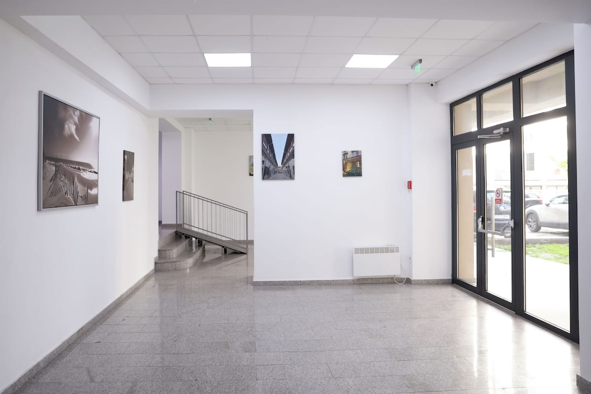 A hallway with a staircase, a radiator, and framed artwork on the walls.