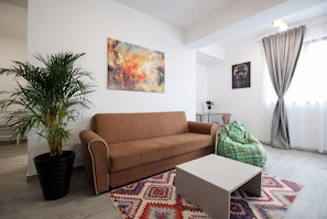 A living room with a sofa, a coffee table, a potted plant, a colorful rug, and artwork on the walls. - Vitan Central Oasis Bucharest (Bucharest)