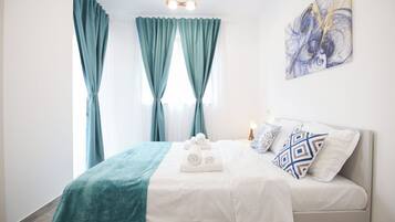 A hotel room with a bed, a bedside lamp, a painting, and curtains.