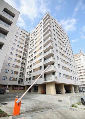 A multi-story residential building with balconies, a parking garage, and a clear sky. - Vitan Central Oasis Bucharest (Bucharest)