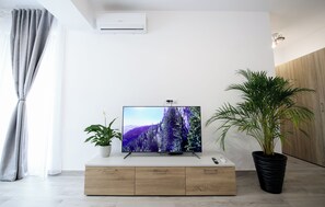 A modern living room with a flat-screen TV, wooden cabinet, potted plants, and an air conditioning unit. - Vitan Central Oasis Bucharest (Bucharest)