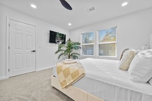 A bedroom with a bed, a TV mounted on the wall, a window with blinds, and a door. - Royal Palm Urban Suites - Spacious 5 bedroom and Close to ATL Downtown (Atlanta)