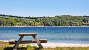 A beach with a picnic table and a clear view of the water and distant hills. - Lovely home in Broager with WiFi (Broager)