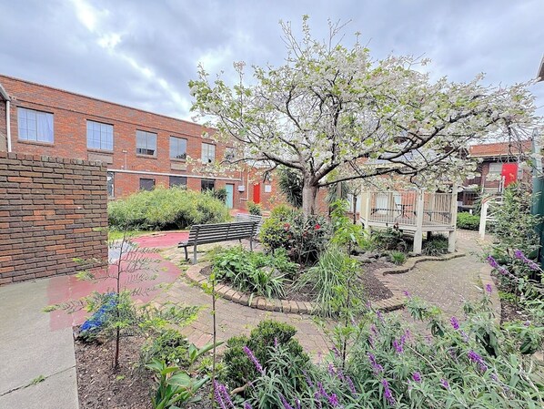 A courtyard with a bench, a tree, and a playground area.