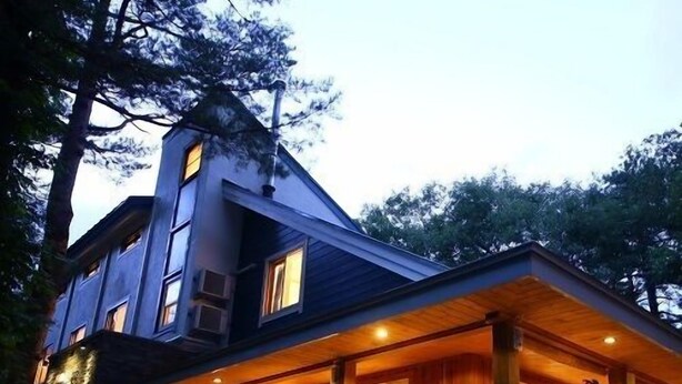 A large, multi-story building with a prominent chimney, large windows, and a covered porch area. - Hakuba Himekawa Onsen Pension Tomato (Hakuba)