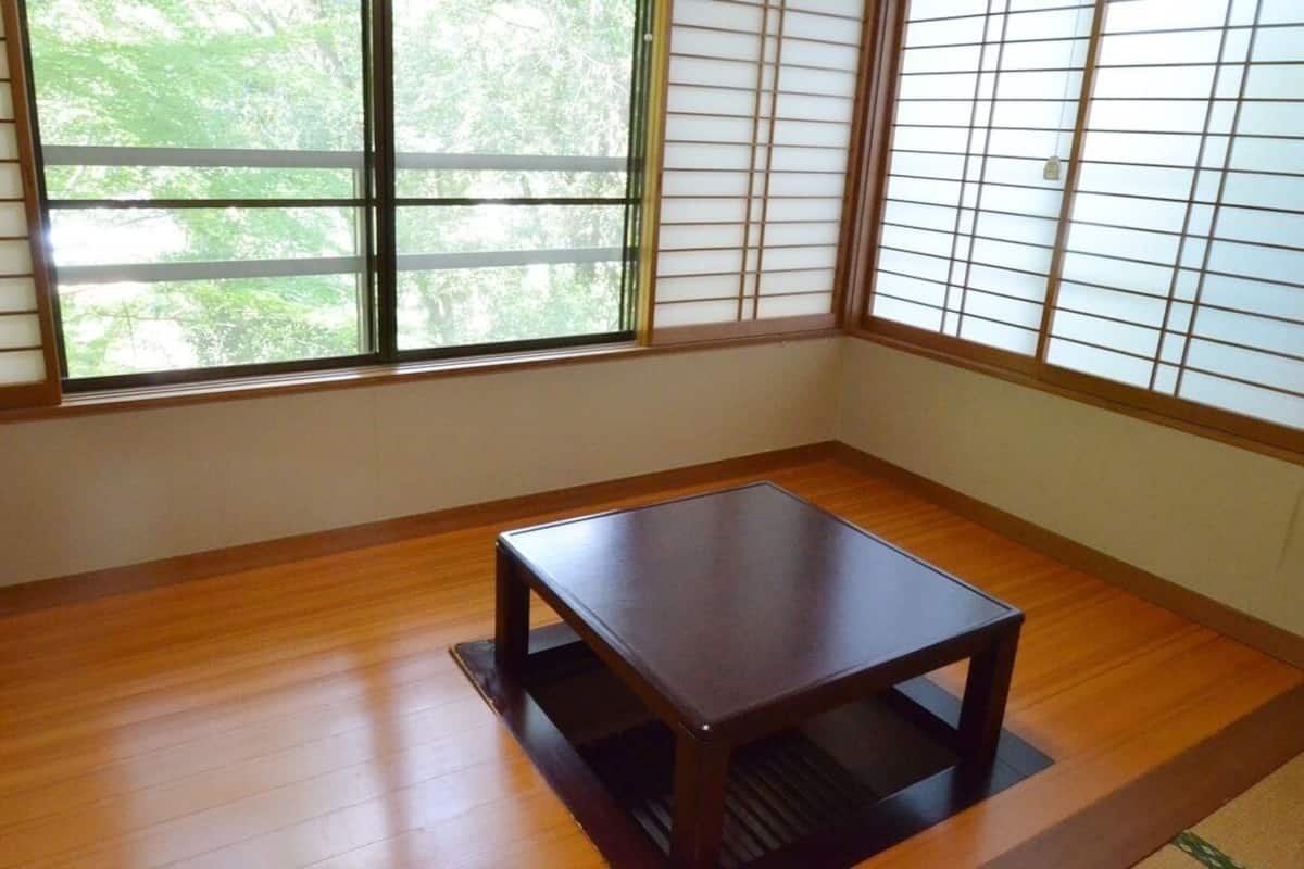 A room with wooden flooring, a small table, and a window with shoji screens.