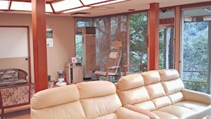 A room with a sofa, a chair, a heater, and a window with a view of trees.