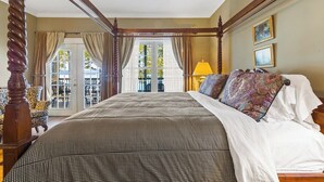 Un letto a baldacchino con copriletto a quadri, una testiera in legno e vista su un patio esterno attraverso una porta vetrata.