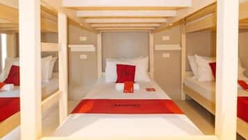 Habitación con literas, un edredón rojo, almohadas blancas y una almohada roja sobre la cama.