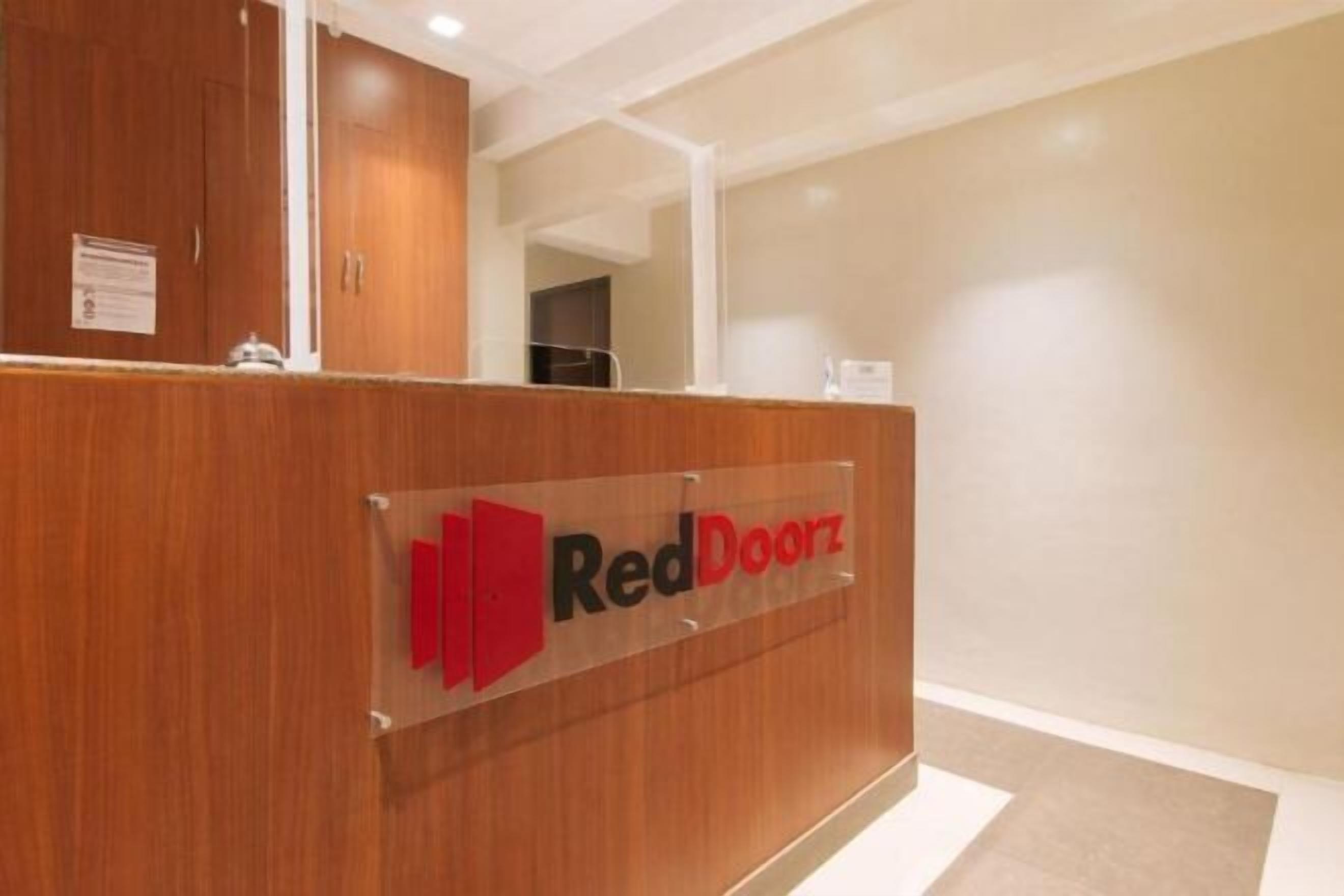 Un mostrador de recepción con un letrero que dice 'RedDoorz' en el vestíbulo de un hotel.