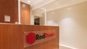 Een receptiebalie met een bord waarop 'RedDoorz' staat in een hotelhal.