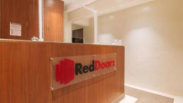 Un mostrador de recepción con un letrero que dice 'RedDoorz' en el vestíbulo de un hotel.