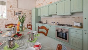 A kitchen with green cabinets, a stove, and a dining table set with plates and cups.